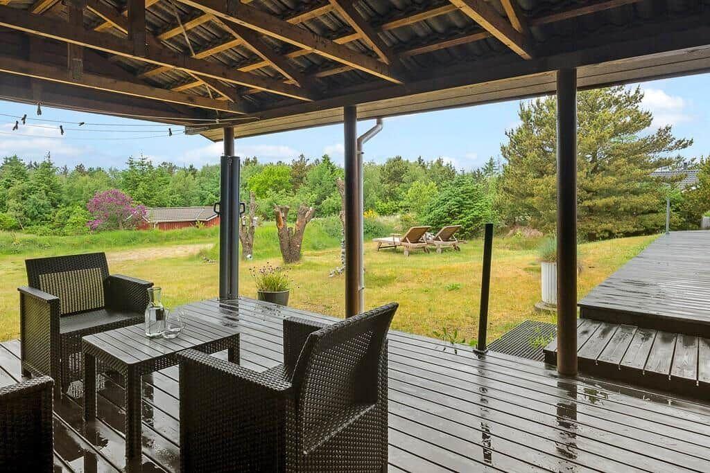 Deck with seating area and view of garden and forest.