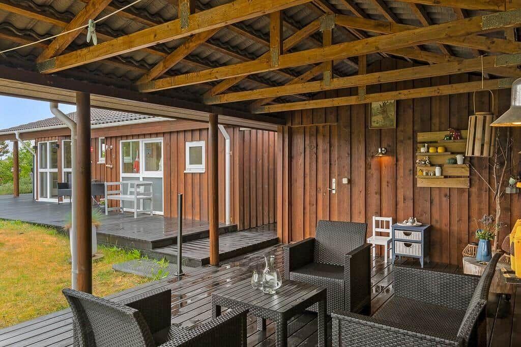 Deck with seating and wooden wall. House with deck visible in background.
