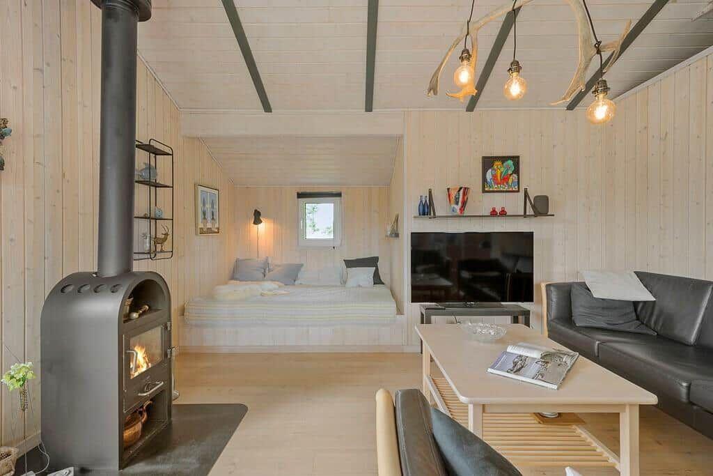 Living area with sofa, fireplace, and bed in background. Ceiling with wood and antlers.