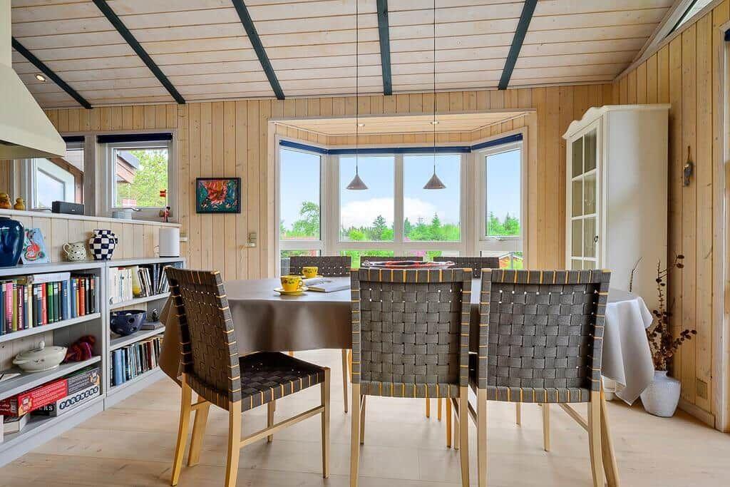 Dining room with table, chairs, and large window. Wooden walls and ceiling.