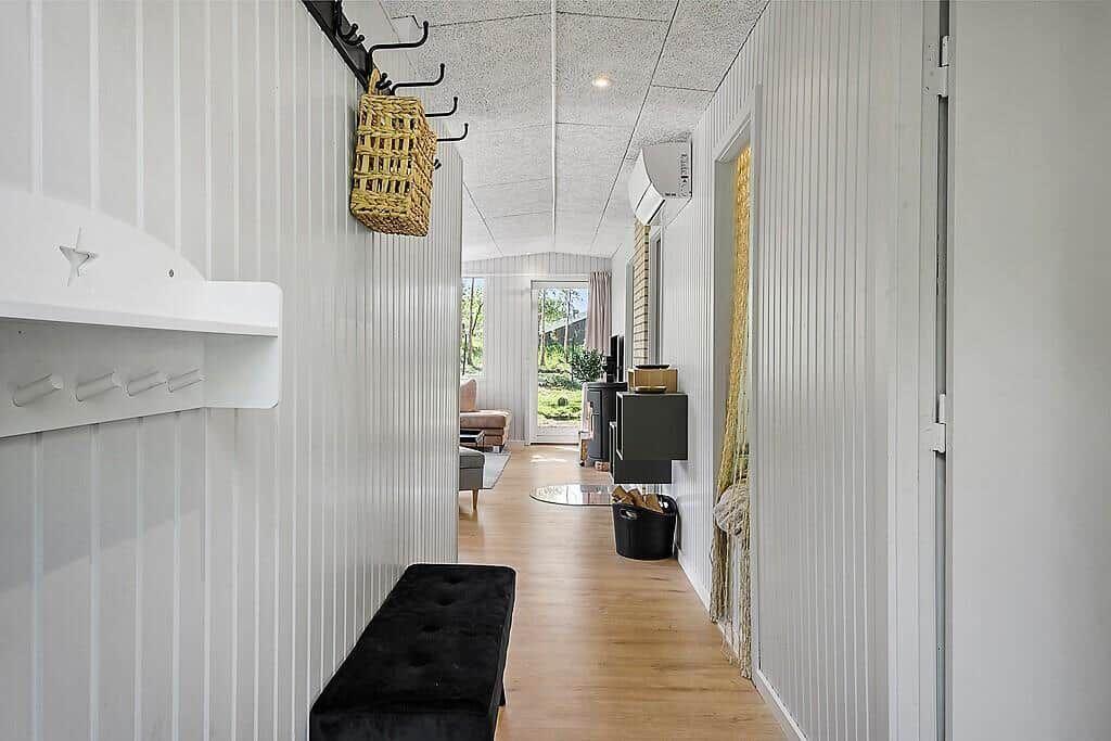 Hallway with wooden floor, white walls, and a bench. A basket hangs on the wall.