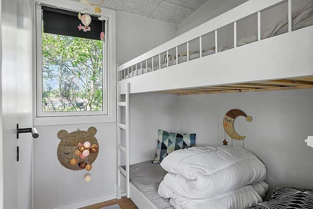 Childrens room with bunk bed, window, and wall decor.