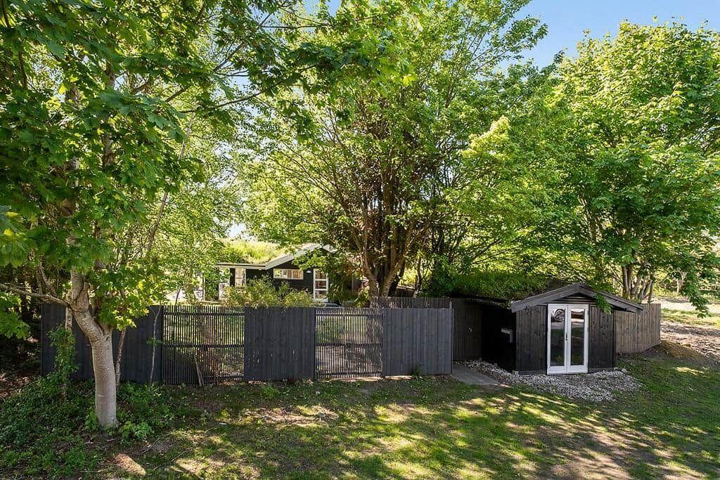 House with wooden garage and fence in the green garden.