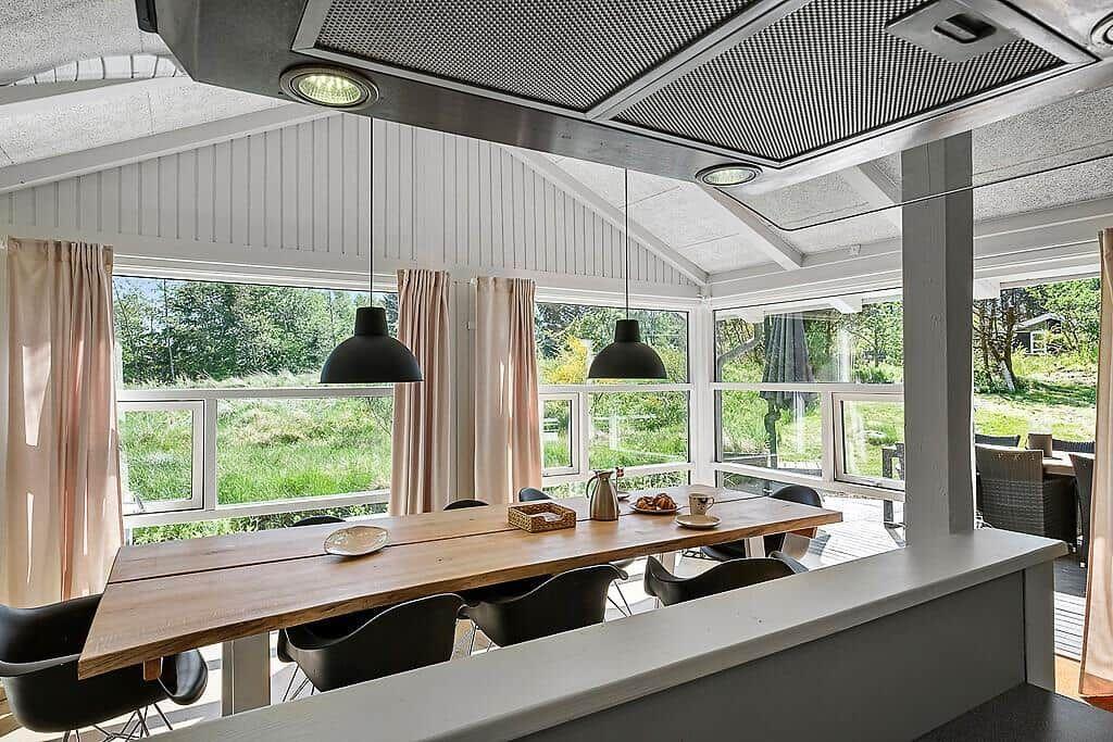 Dining area with wooden table, black chairs, and view of green outdoor space.
