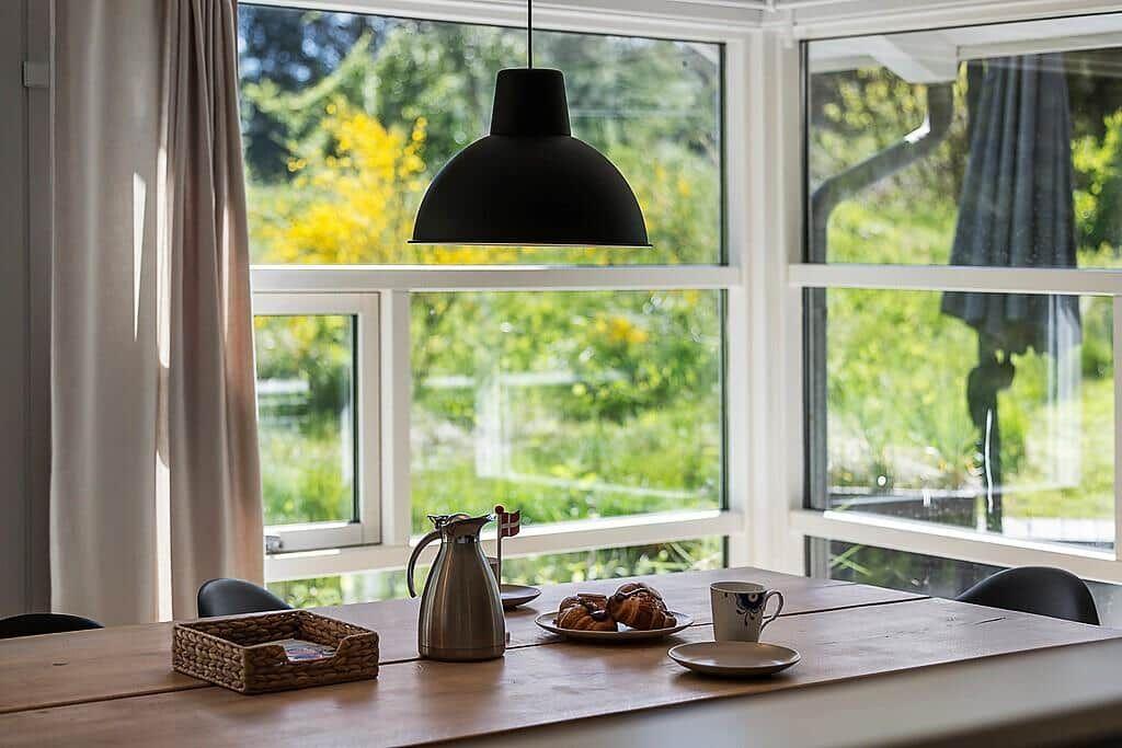 Dining table with coffee pot, croissants, and view of green garden.