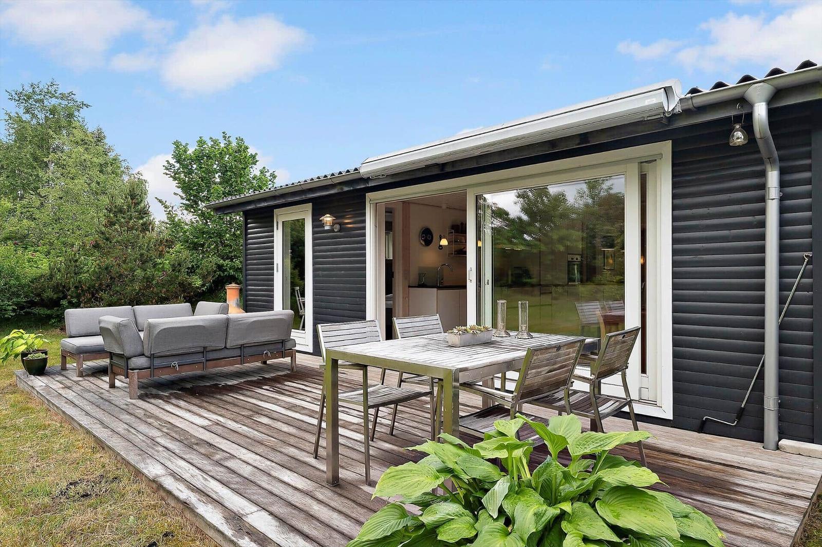 Deck with seating group and dining table. Sliding glass doors lead to kitchen-living area.