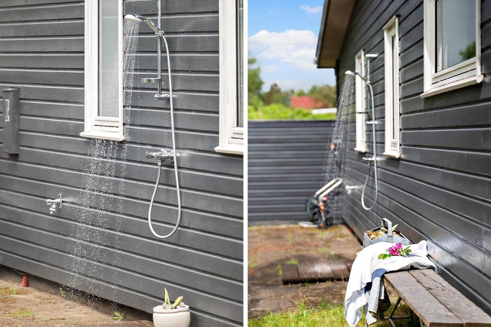 Outdoor shower on gray wooden house with window and wooden bench
