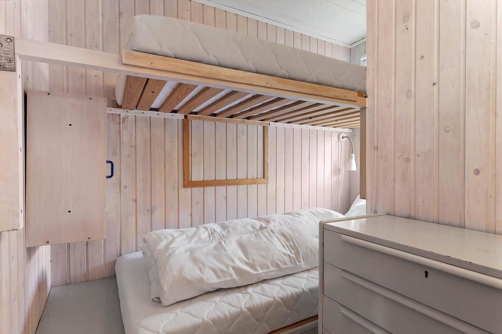 Room with two beds and wood-paneled walls.