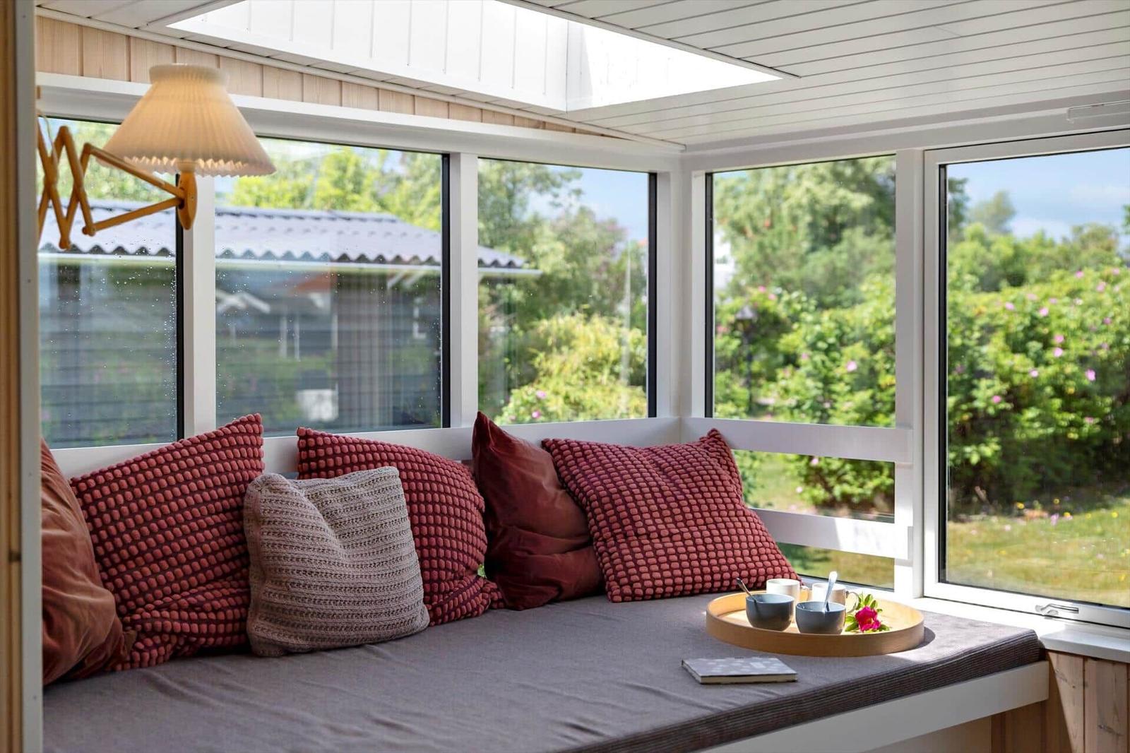 Seating bench with cushions and tray by window with garden view