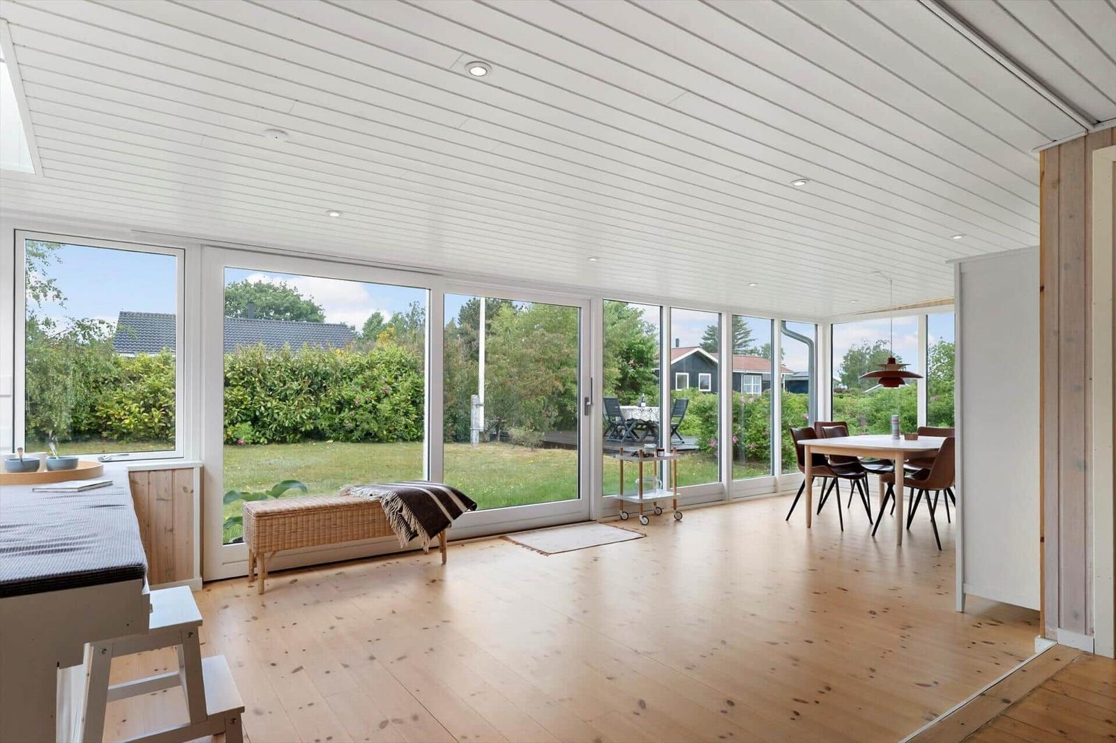 Large living and dining area with wooden floor and large windows overlooking the garden.