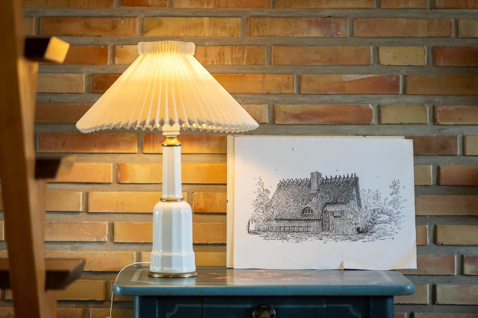 Eine Lampe und eine Zeichnung auf einem Tisch vor einer Ziegelwand.
