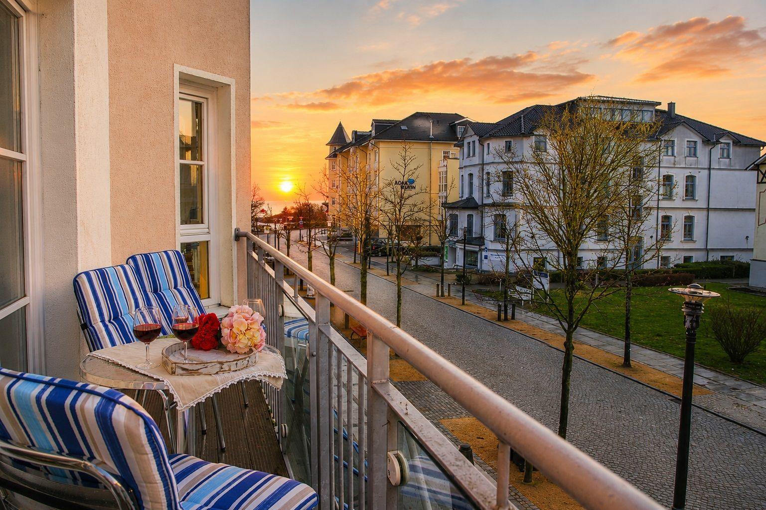 Balkon mit Stühlen und Tisch. Sonnenuntergang über Straße und Gebäude.