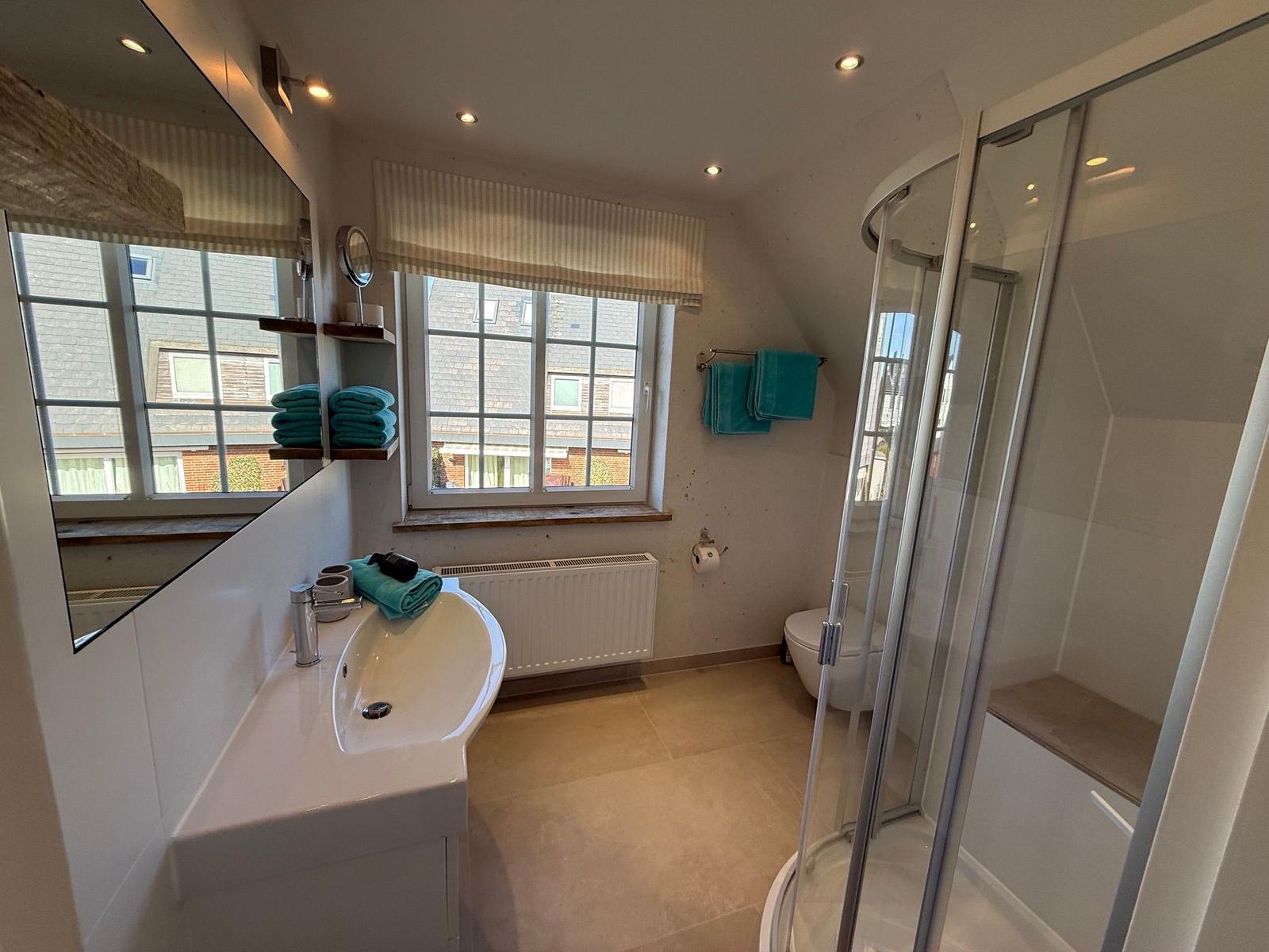 Badezimmer mit Dusche, Waschbecken und Fenster