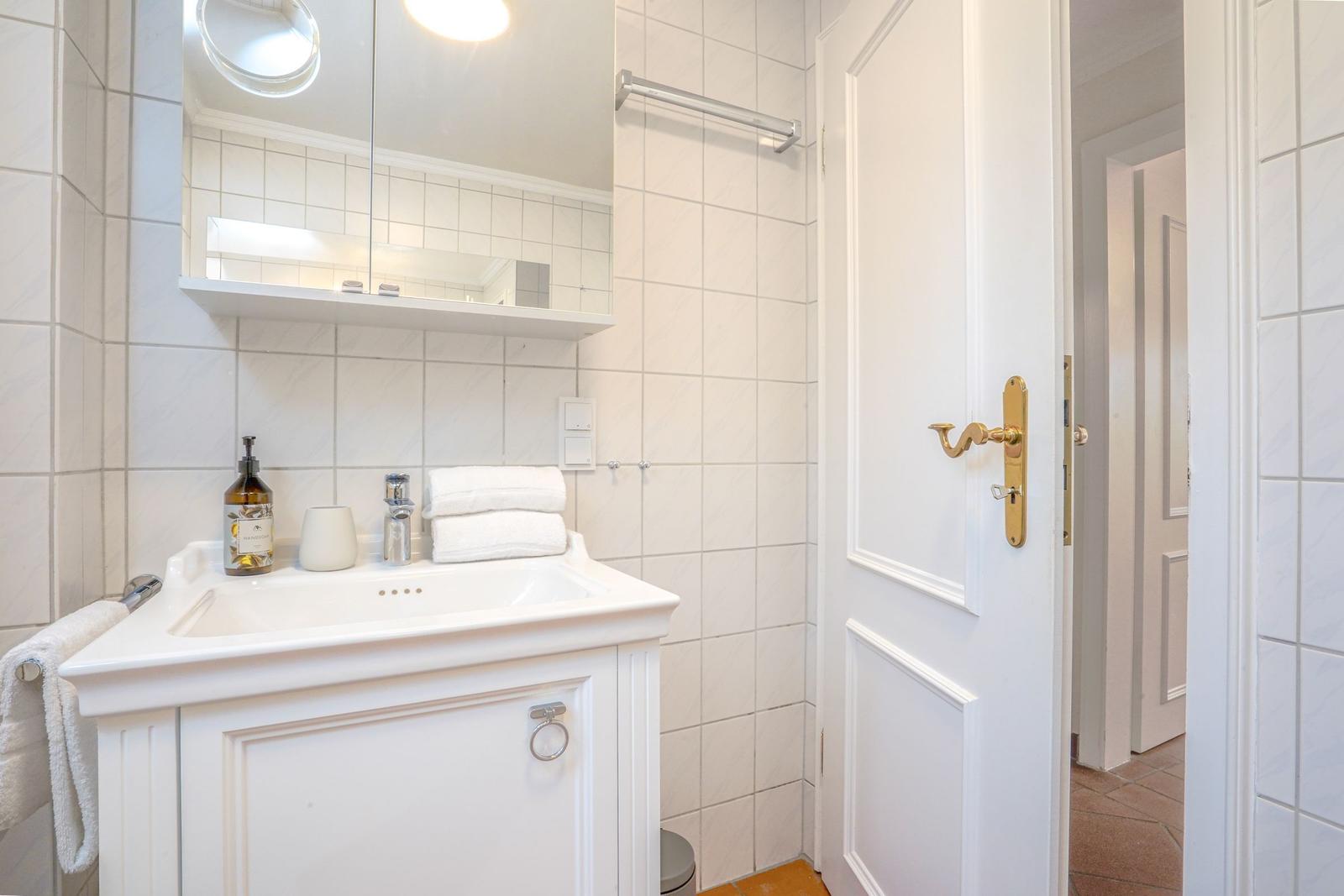 Badezimmer mit Waschbecken, Spiegel und Duschbereich.