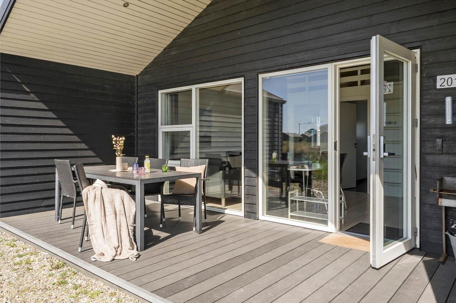 Terrasse mit Tisch, Stühlen und Blick ins Haus. Glastüren führen in den Innenraum.