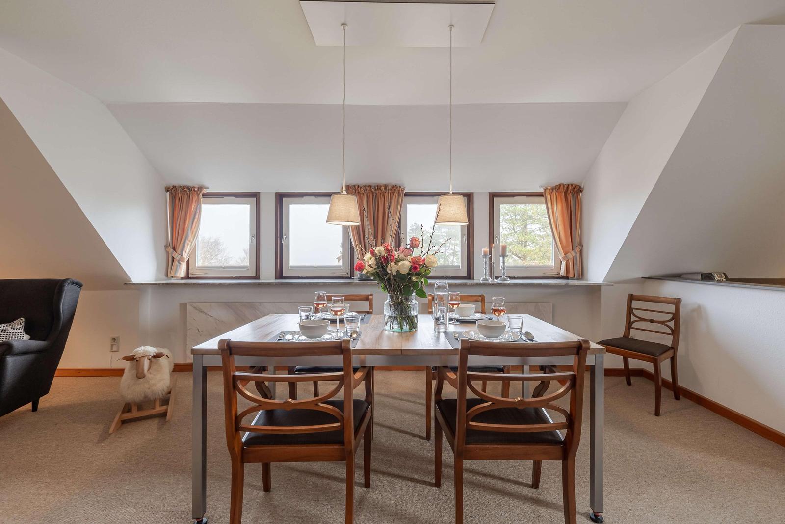 Esszimmer mit Tisch, Stühlen und Fenstern. Dekoration mit Blumen und Kerzen.