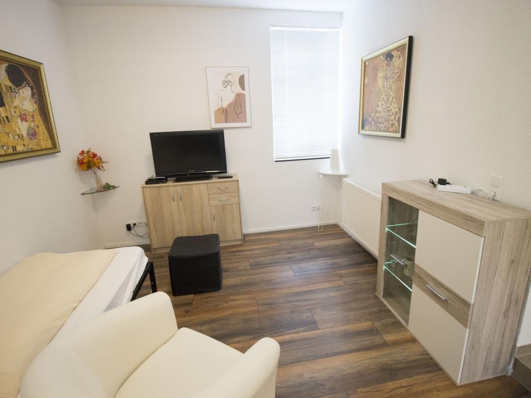 Ein Zimmer mit Bett, Fernseher, Schränken und Fenster mit Jalousie.
