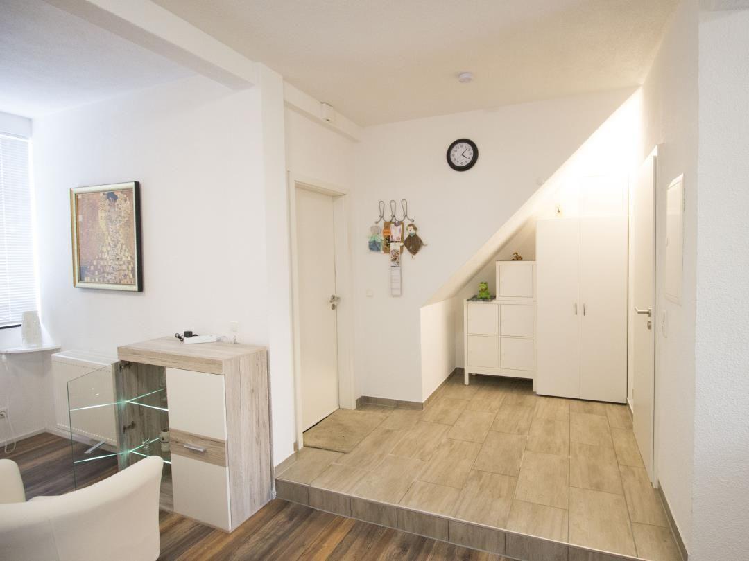 Eingangsbereich mit Garderobe, Uhr und Bild an der Wand.