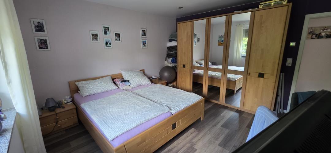 Schlafzimmer mit Doppelbett, Kleiderschrank und Wandbildern.