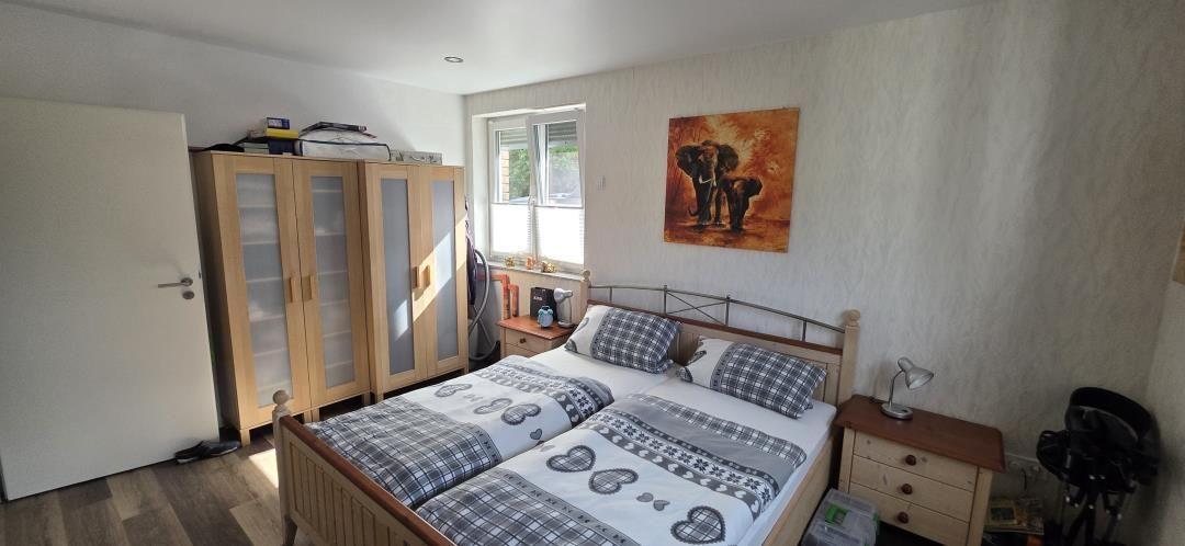 Schlafzimmer mit Doppelbett, Kleiderschrank und Fenster. Wandbild mit Elefanten.