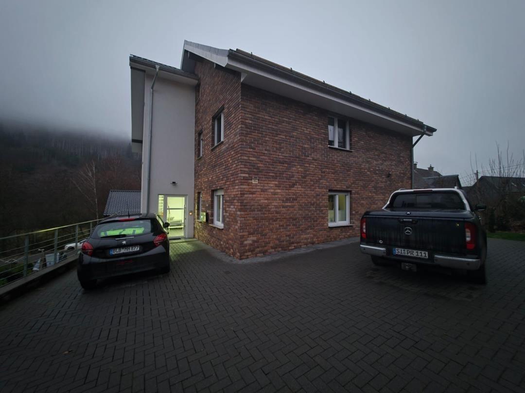 Zweistöckiges Haus mit Backsteinfassade und Parkplatz für zwei Fahrzeuge.