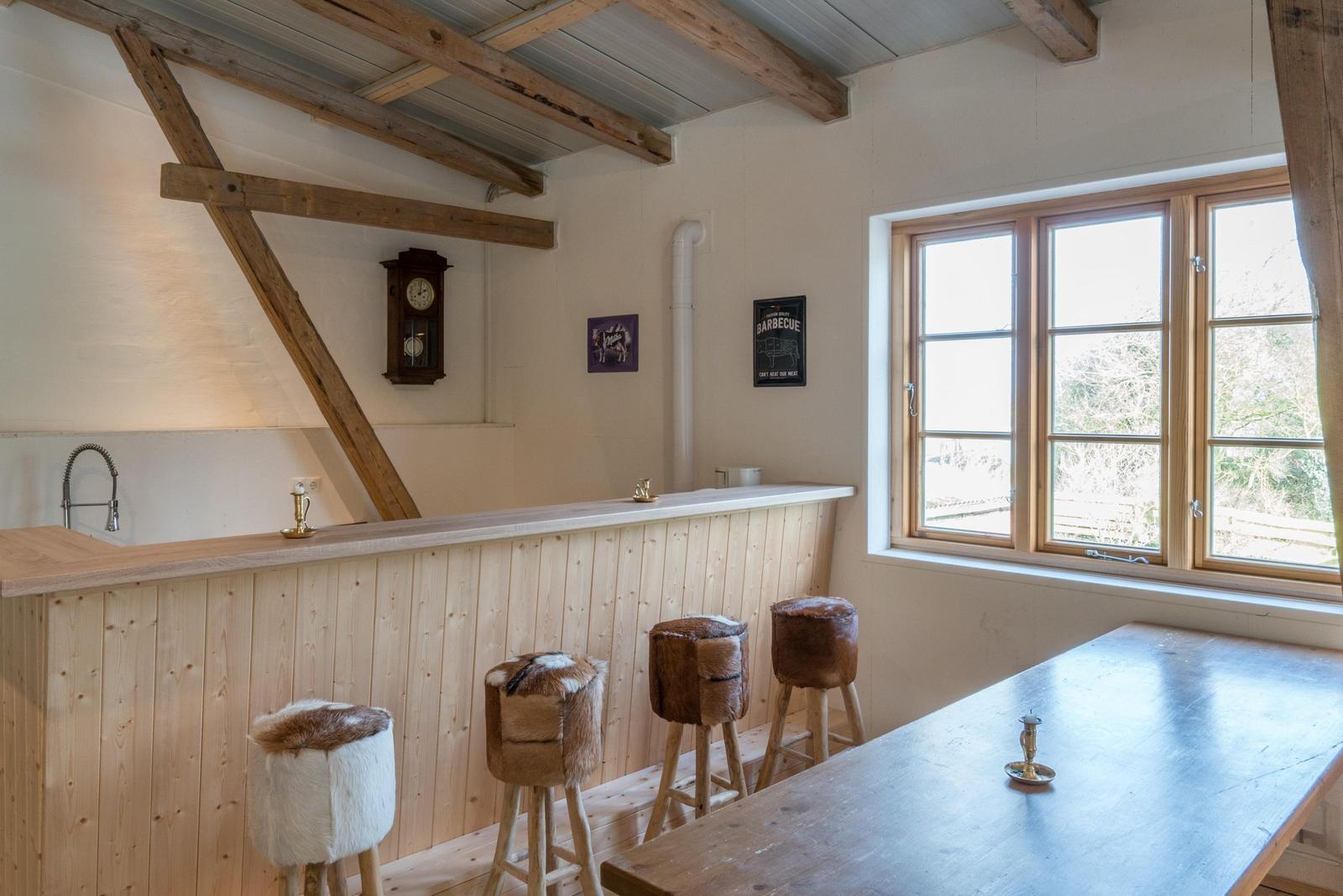 Raum mit Holzbar, Fellhockern und Fenster zur Aussicht