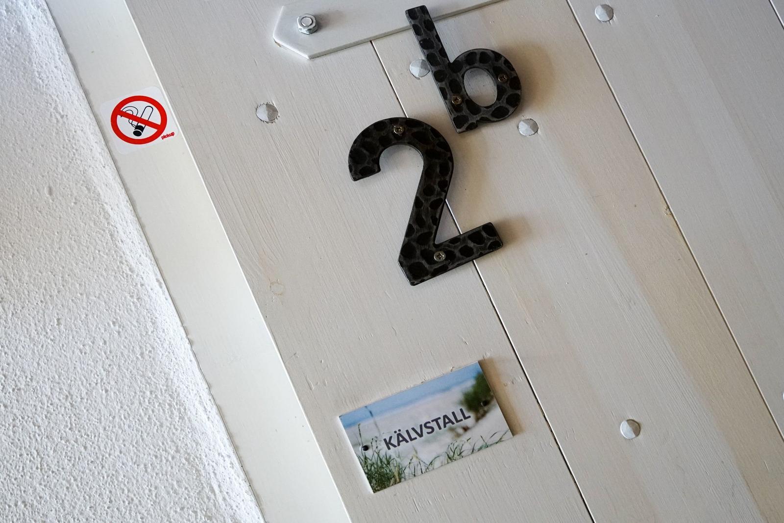 Tür mit Hausnummer 2b und Schild KÄLVSTALL. Rauchverbotsschild angebracht.