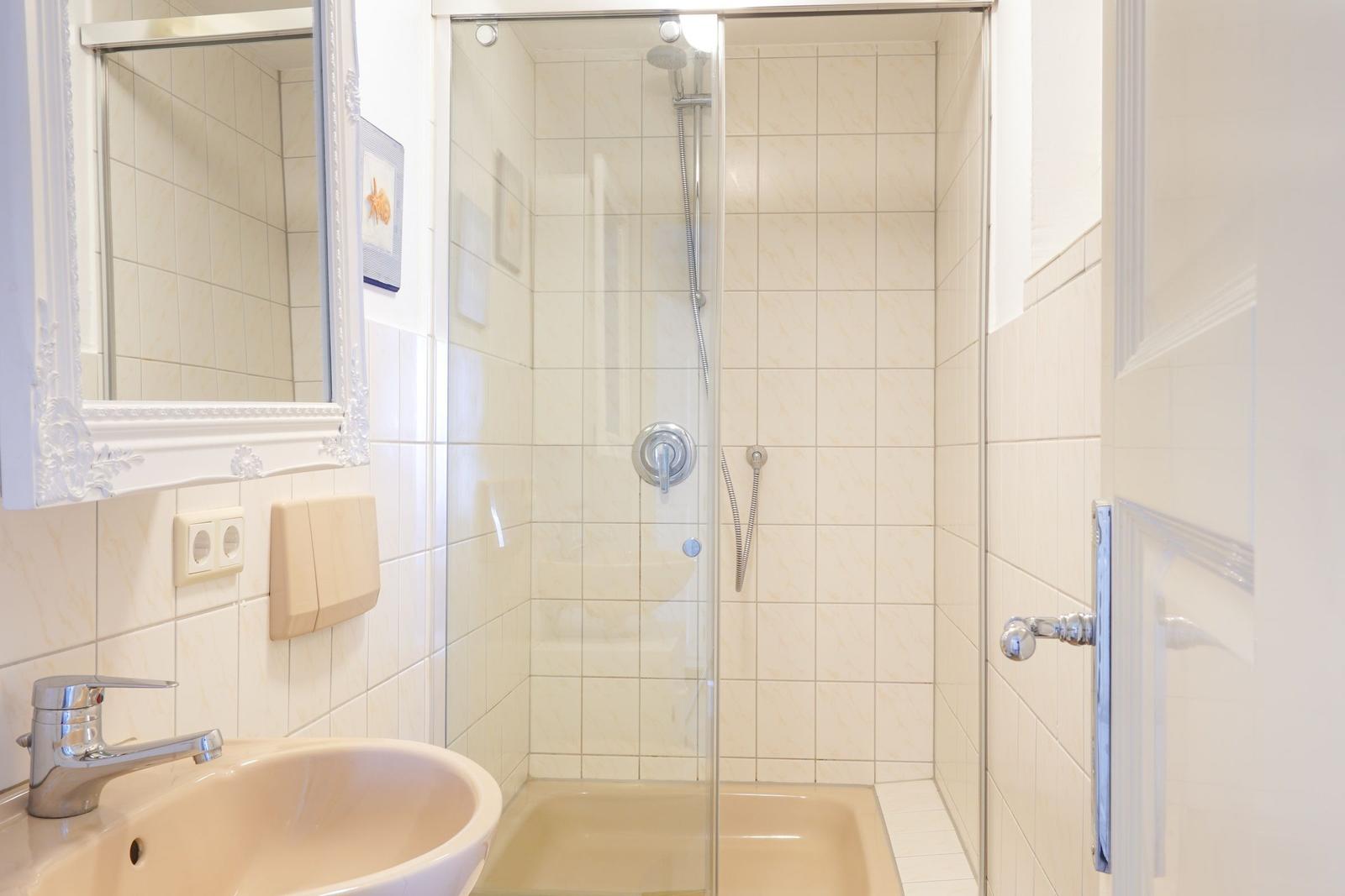 Bad mit Dusche, Waschbecken und Spiegel