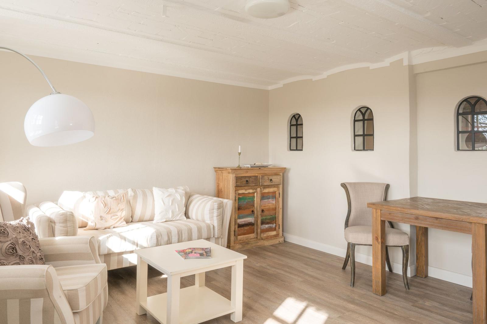 Wohn- und Essbereich mit Sofa, Tisch und Stuhl. Holzfußboden und weiße Wände.