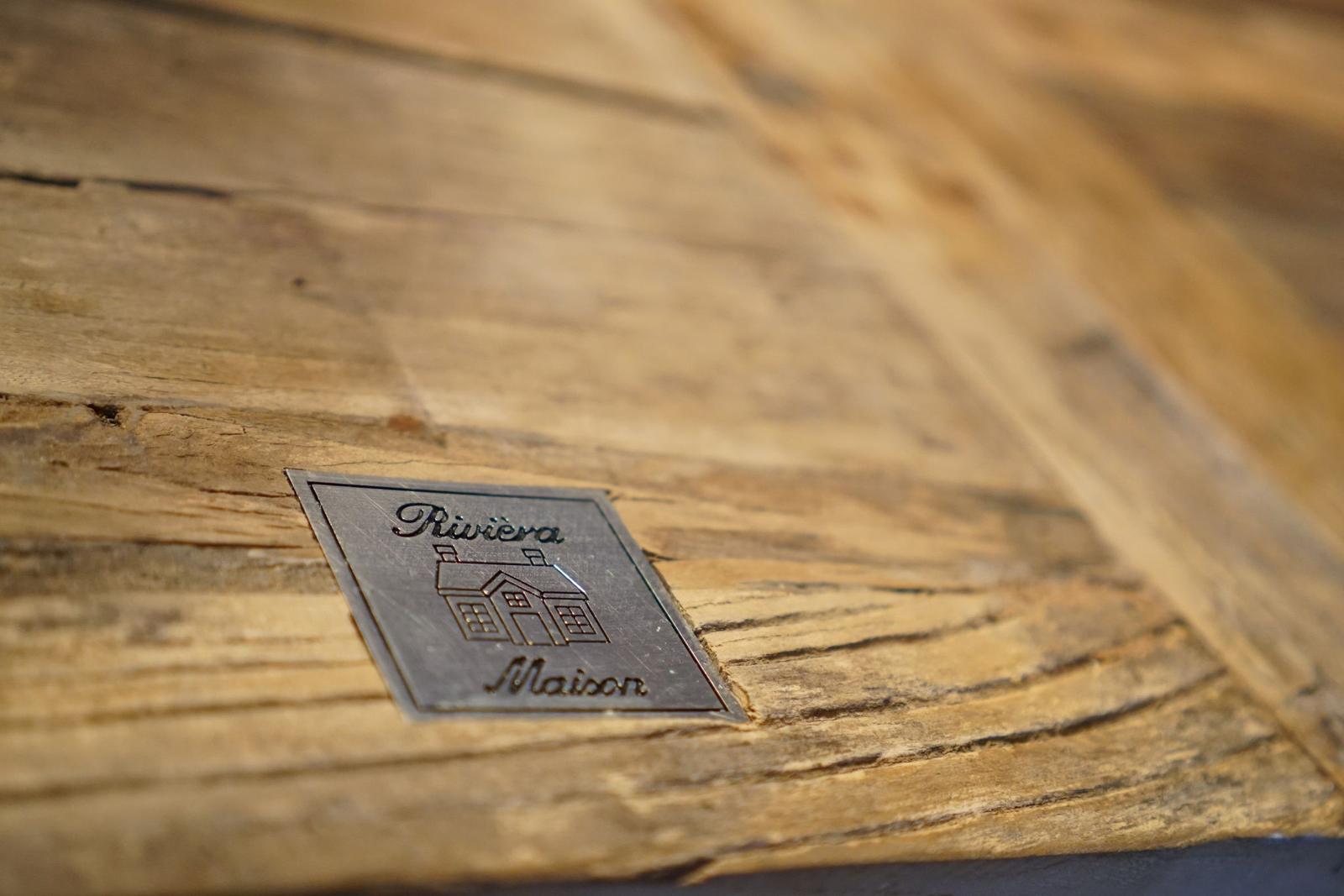 Metallplakette mit Hauszeichen auf Holzoberfläche