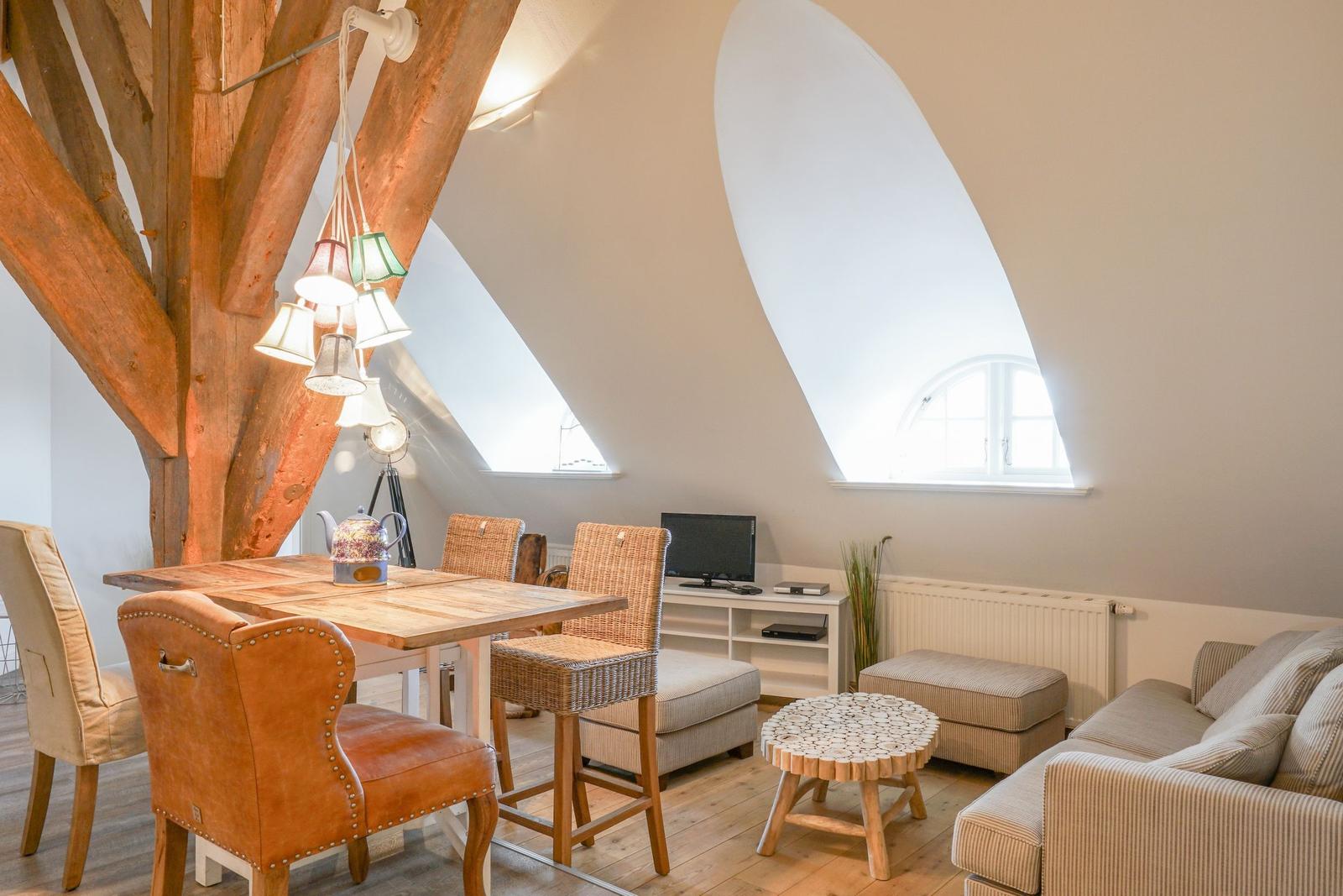 Wohn- und Essbereich mit Holzdecke, Tisch, Stühlen und Sofa.