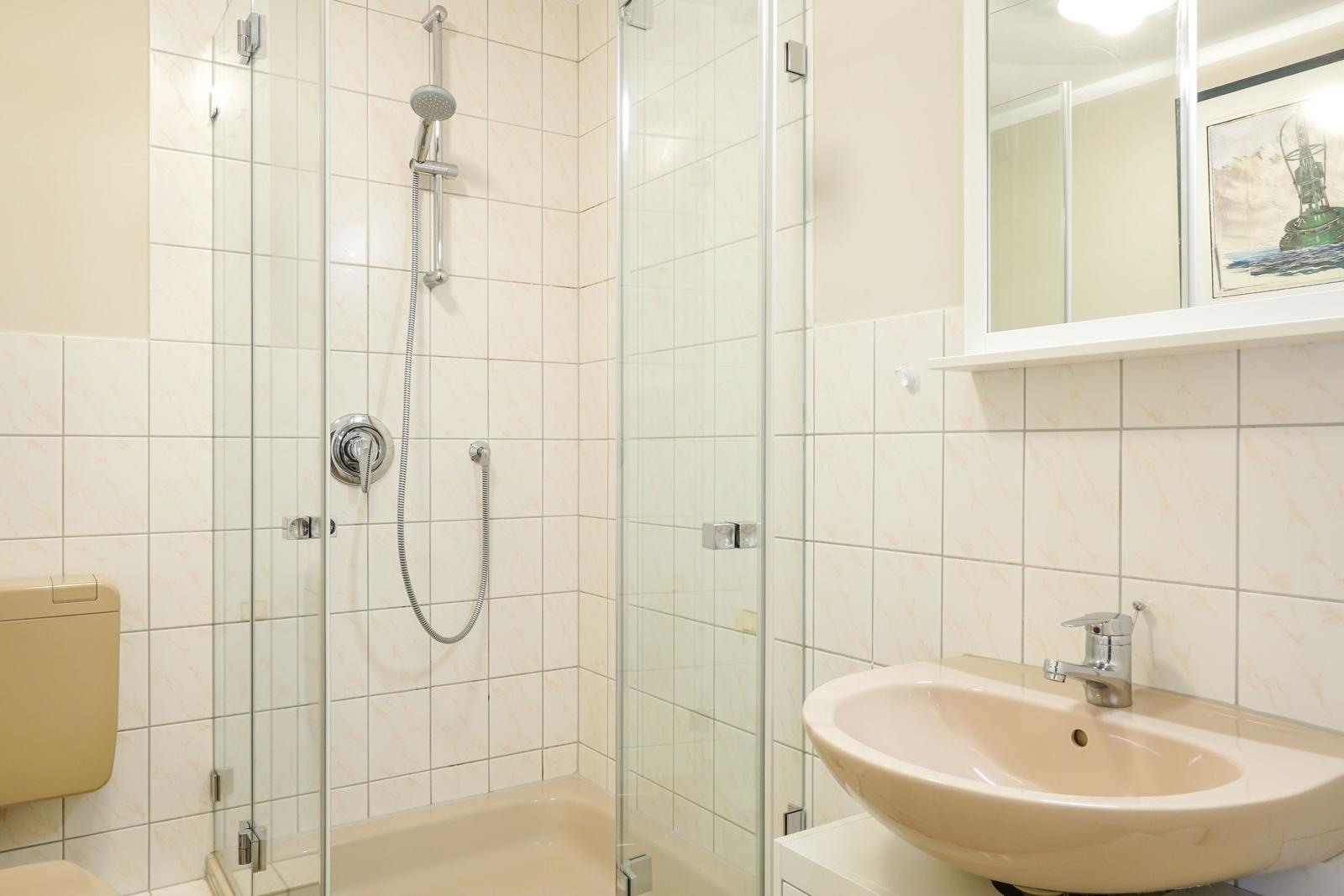 Badezimmer mit Dusche, Waschbecken und Spiegel