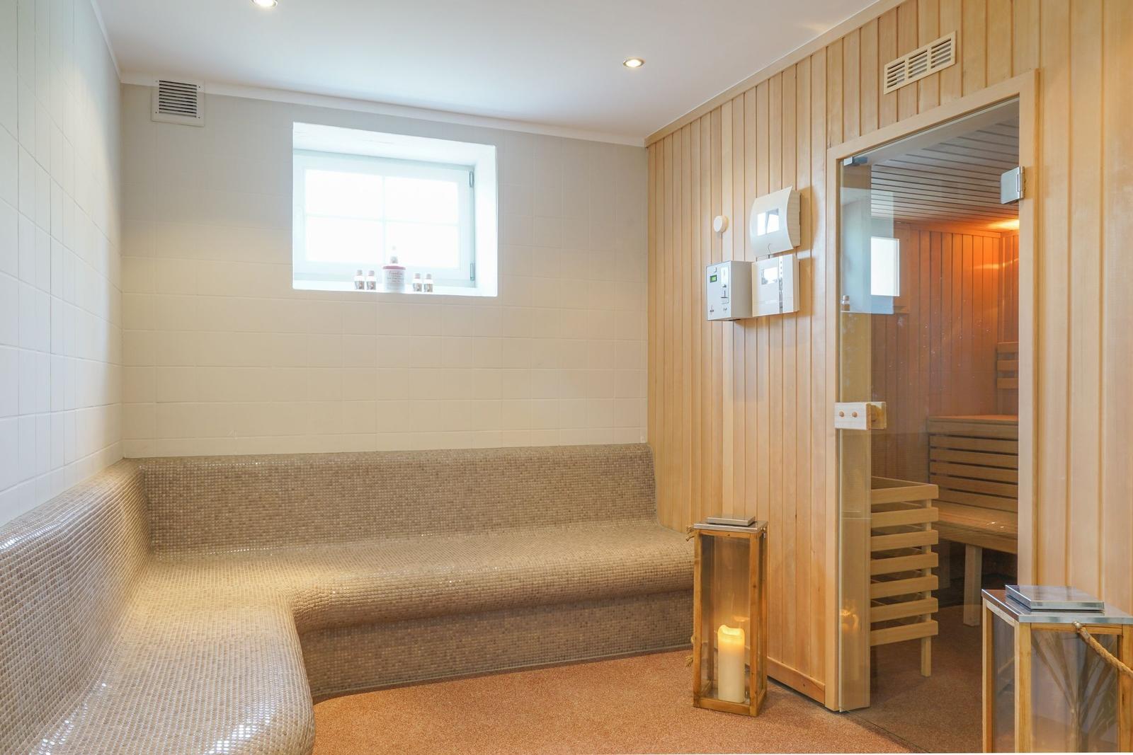 Saunaraum mit Holzwand und Sitzbank. Durchgang zu einer weiteren Sauna.
