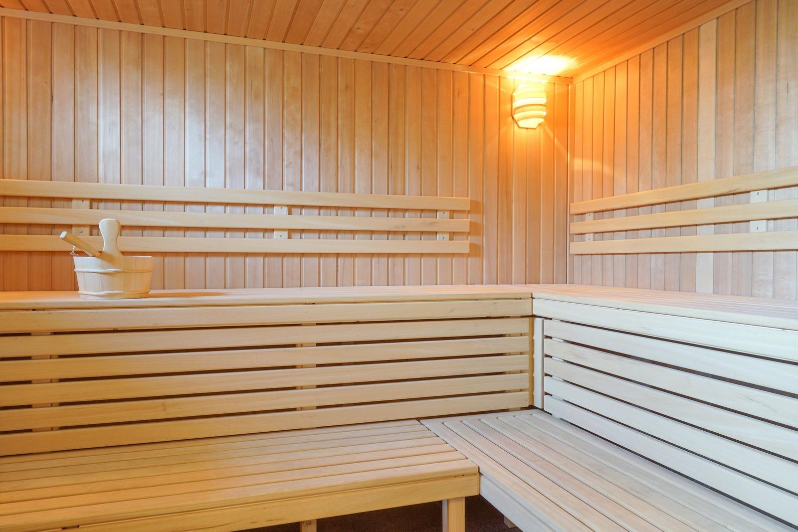 Holzsauna mit Sitzbänken und Eimer. Decke und Wände aus Holz.