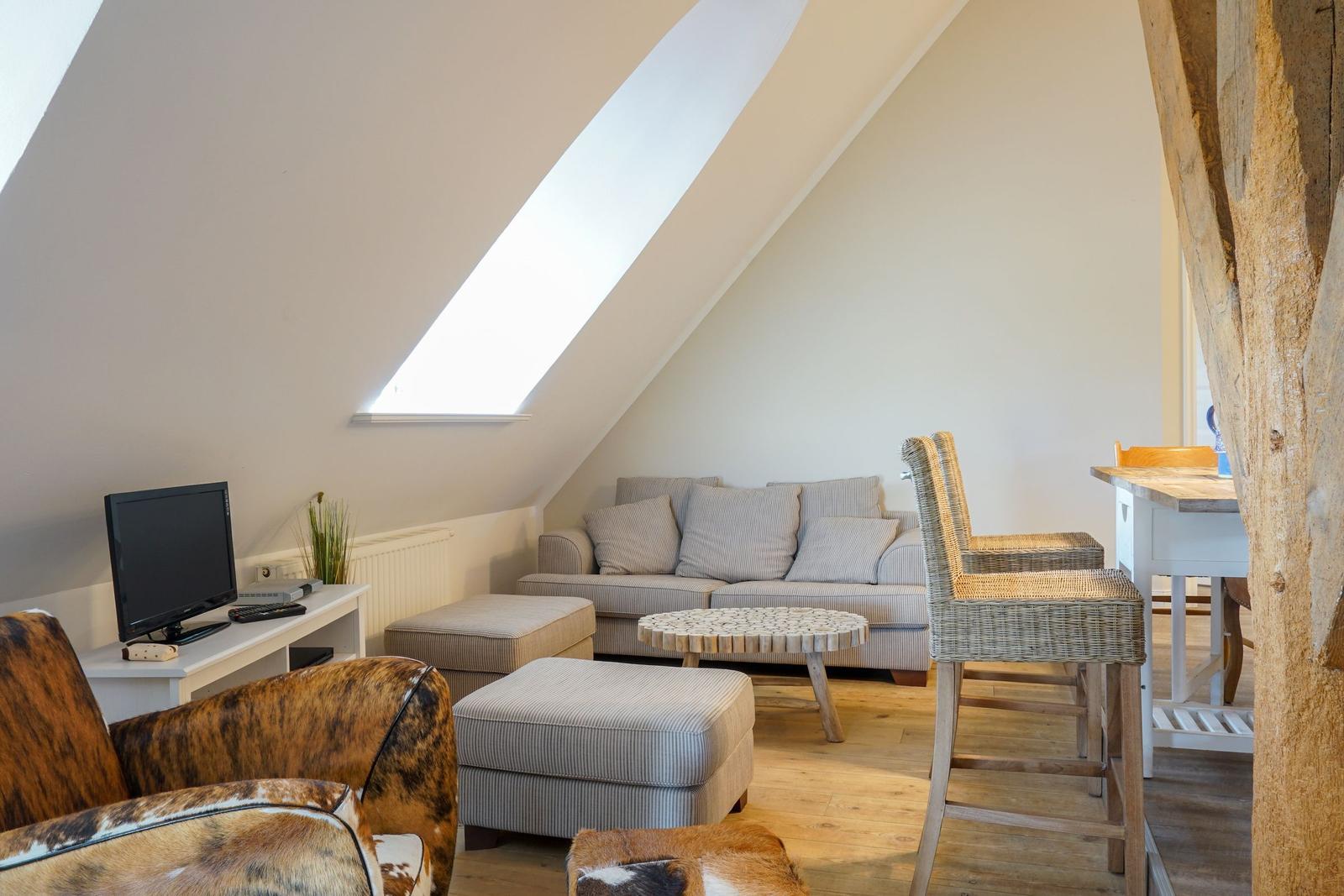Wohnbereich mit Sofa, Sitzbank und Fernseher unter Dachschräge