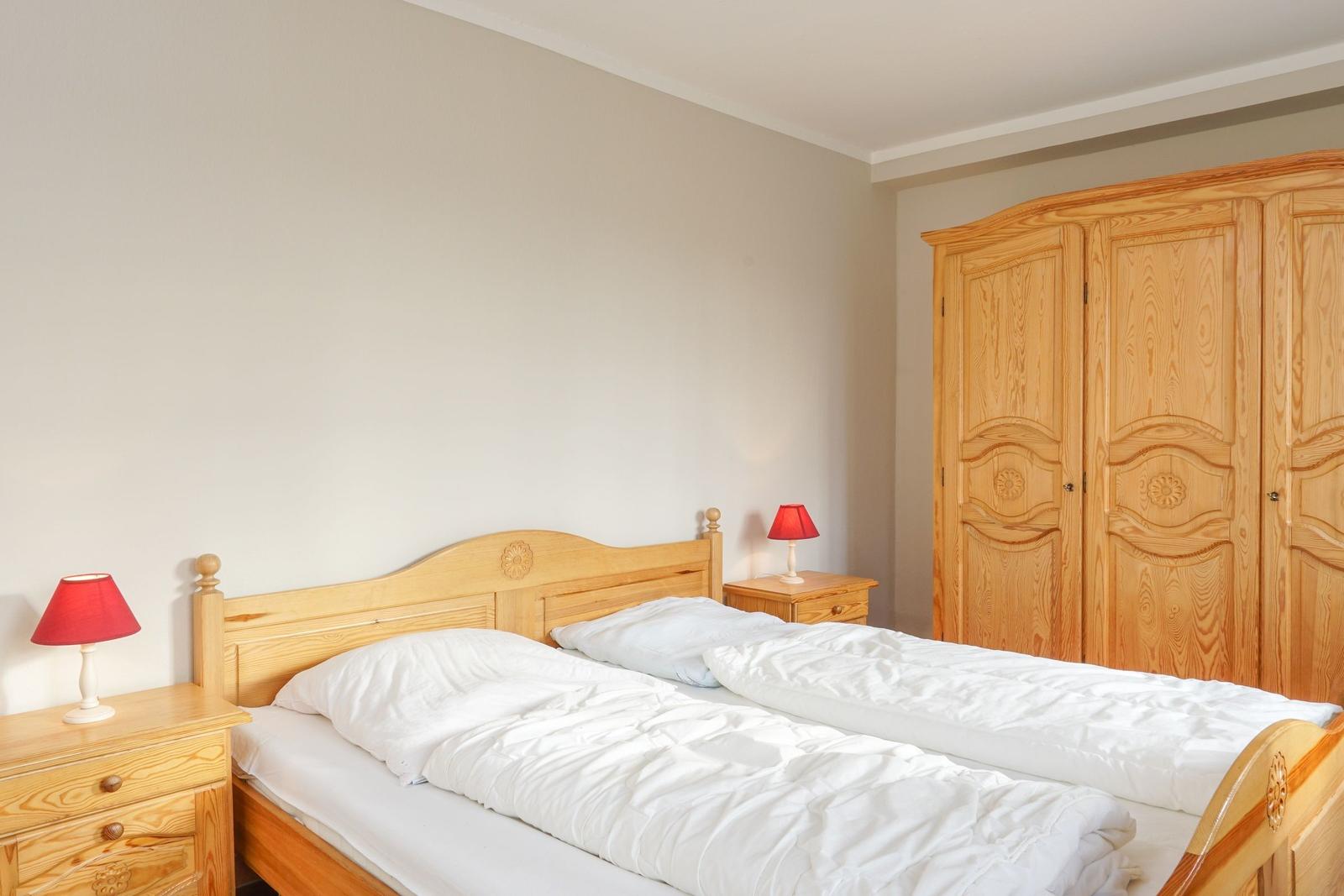 Schlafzimmer mit Holzbett, Nachttischen und Kleiderschrank.