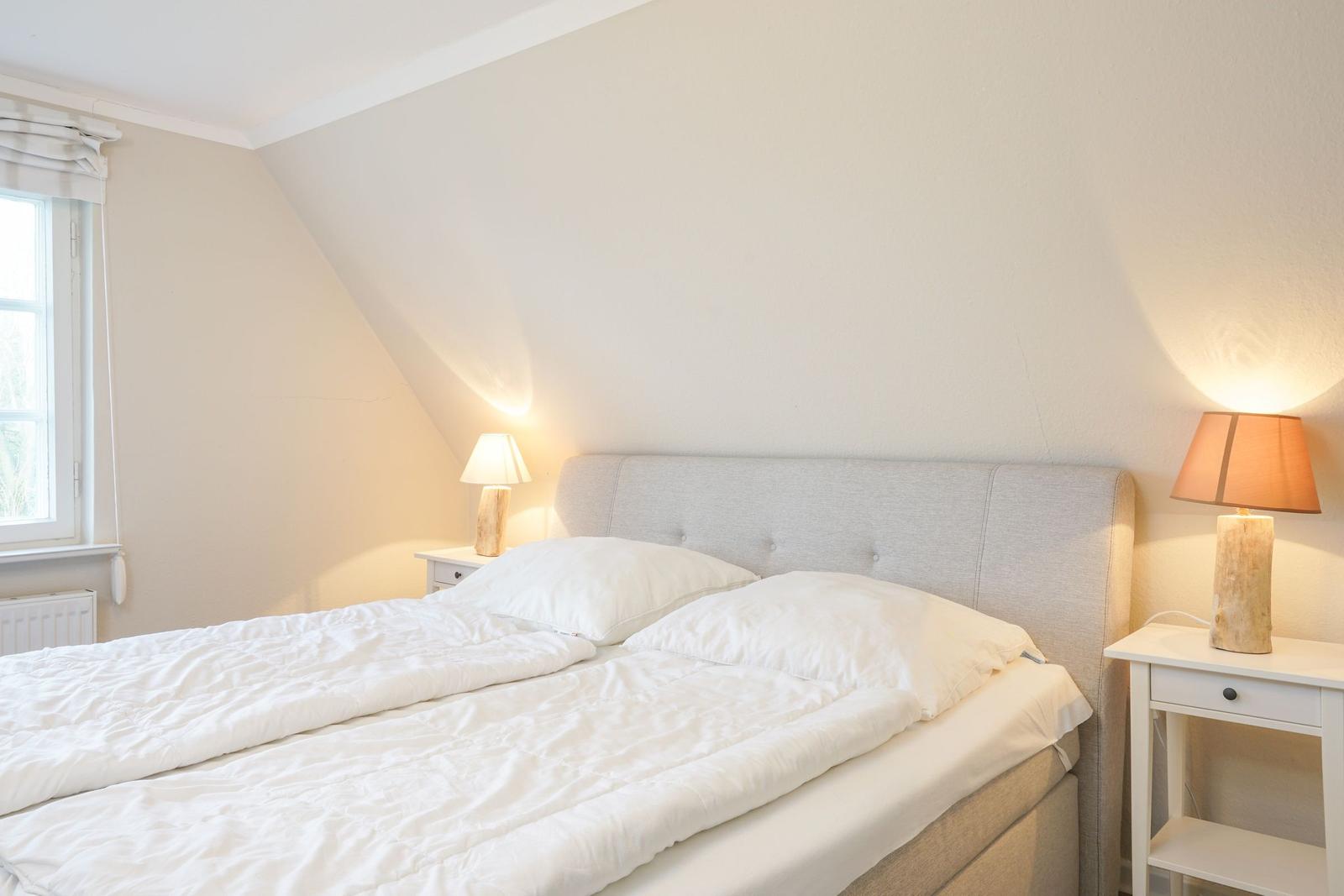 Ein Schlafzimmer mit Doppelbett, zwei Nachttischen und einem Fenster.