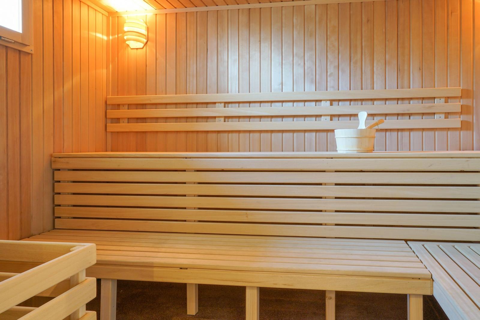 Sauna mit Holzbänken und Eimer mit Löffel.