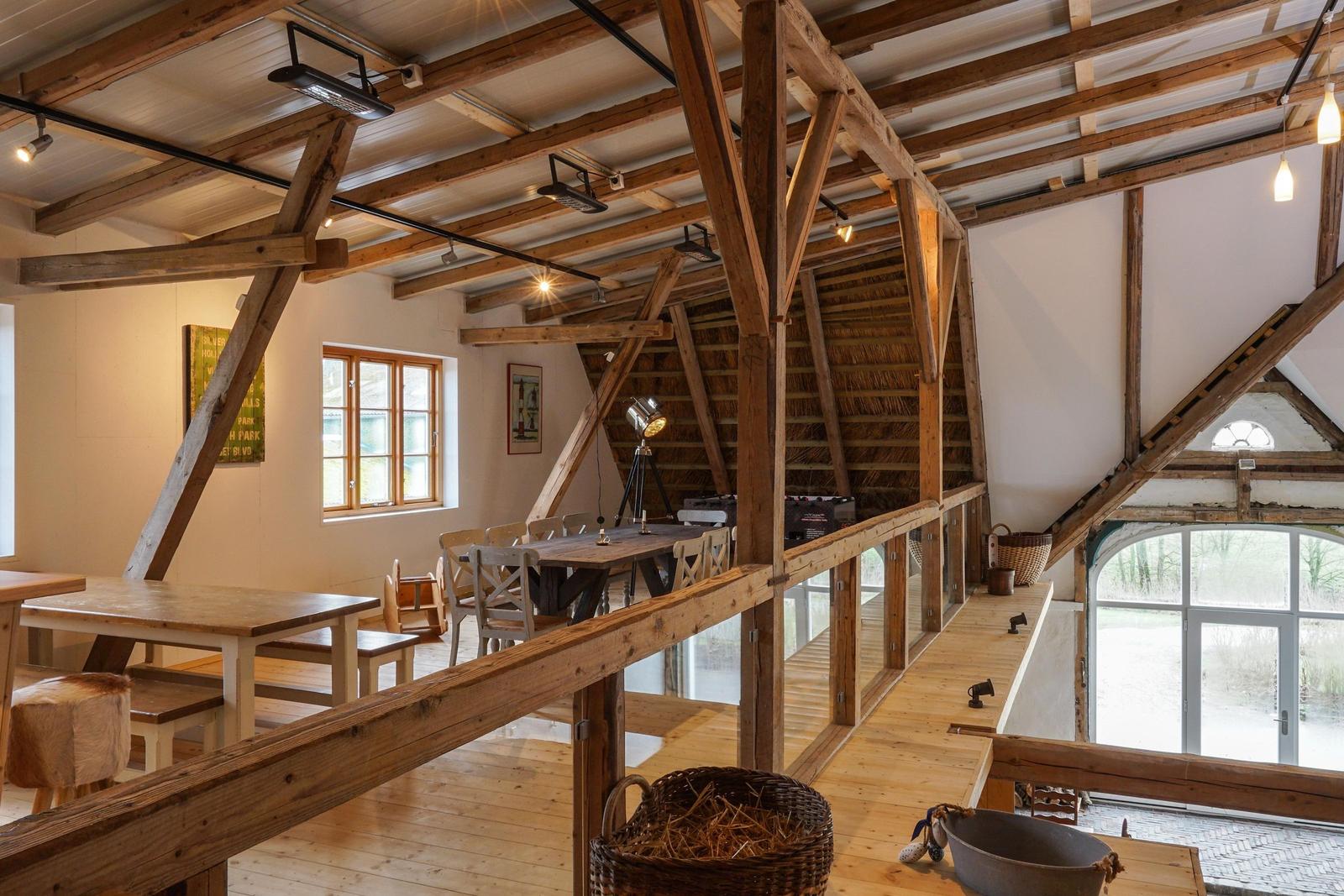 Großes Wohnzimmer mit Holzdecke, Tisch und Stühlen, Fenster und Sicht auf Außenbereich.
