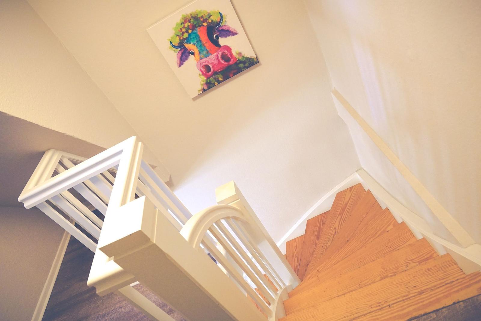 Haus mit Holztreppe und farbigem Wandbild einer Kuh