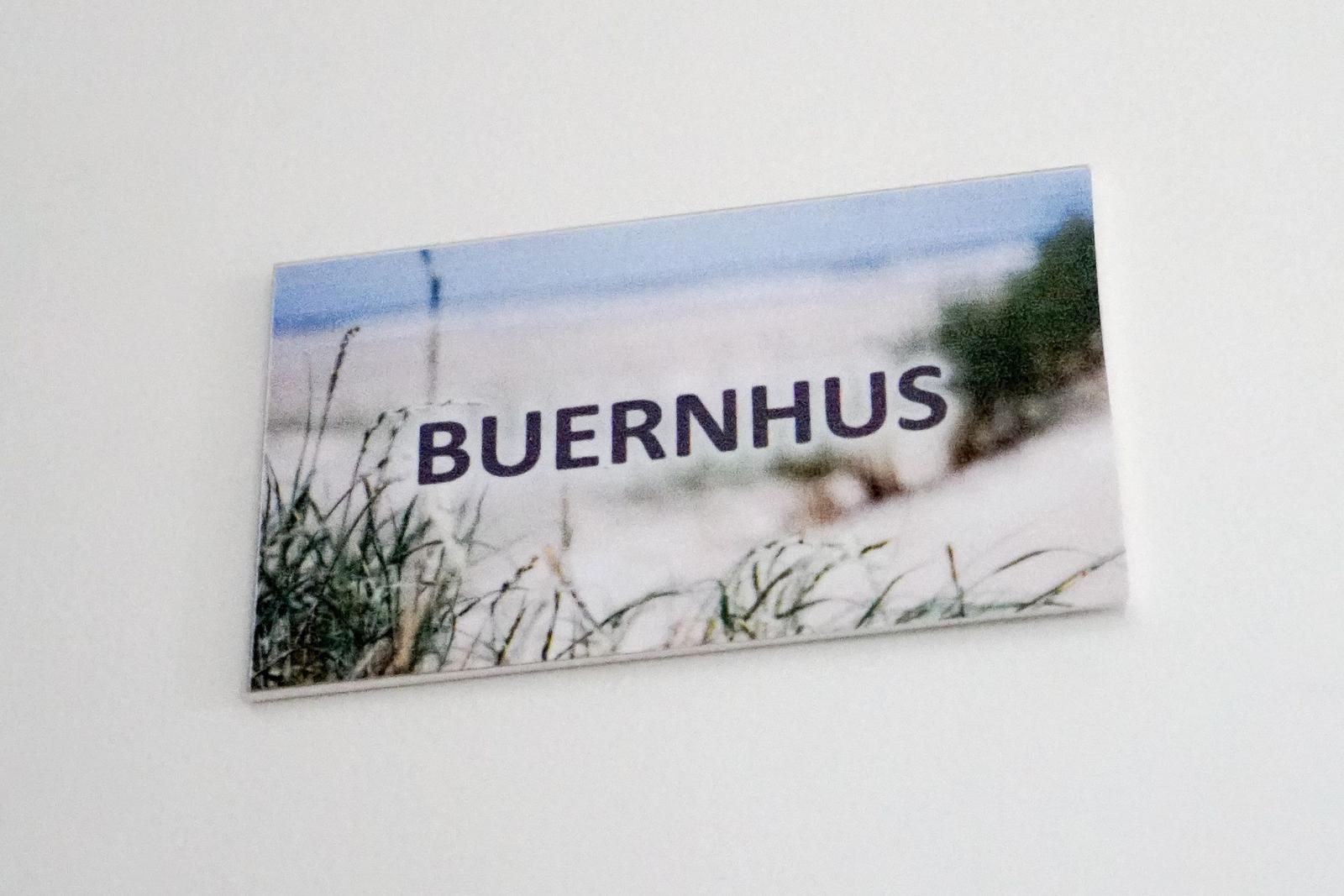 Schild mit der Aufschrift BUERNHUS vor Strandvegetation