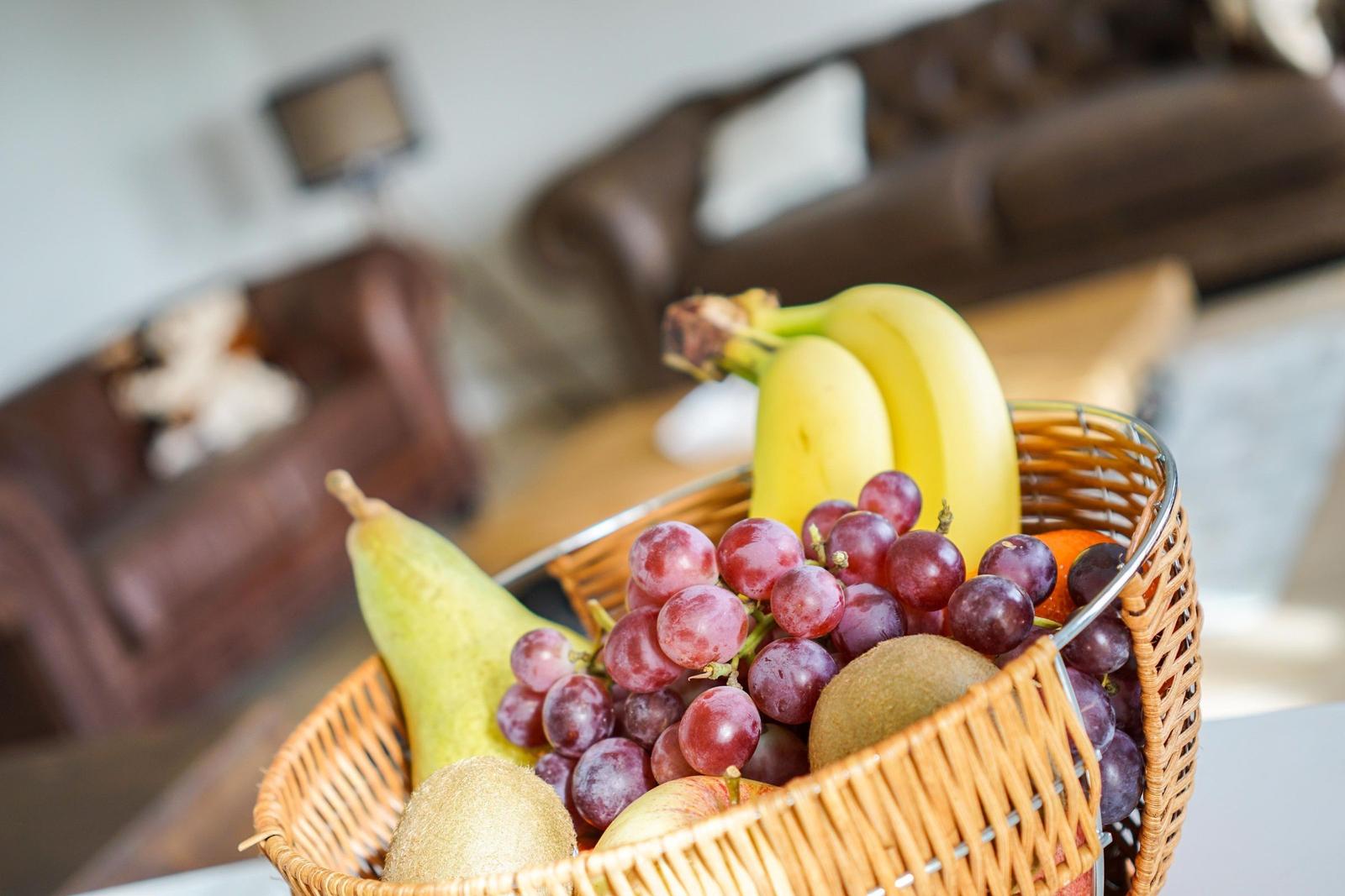Eine Schale mit Obst steht im Vordergrund. Im Hintergrund ist ein Sofa zu sehen.