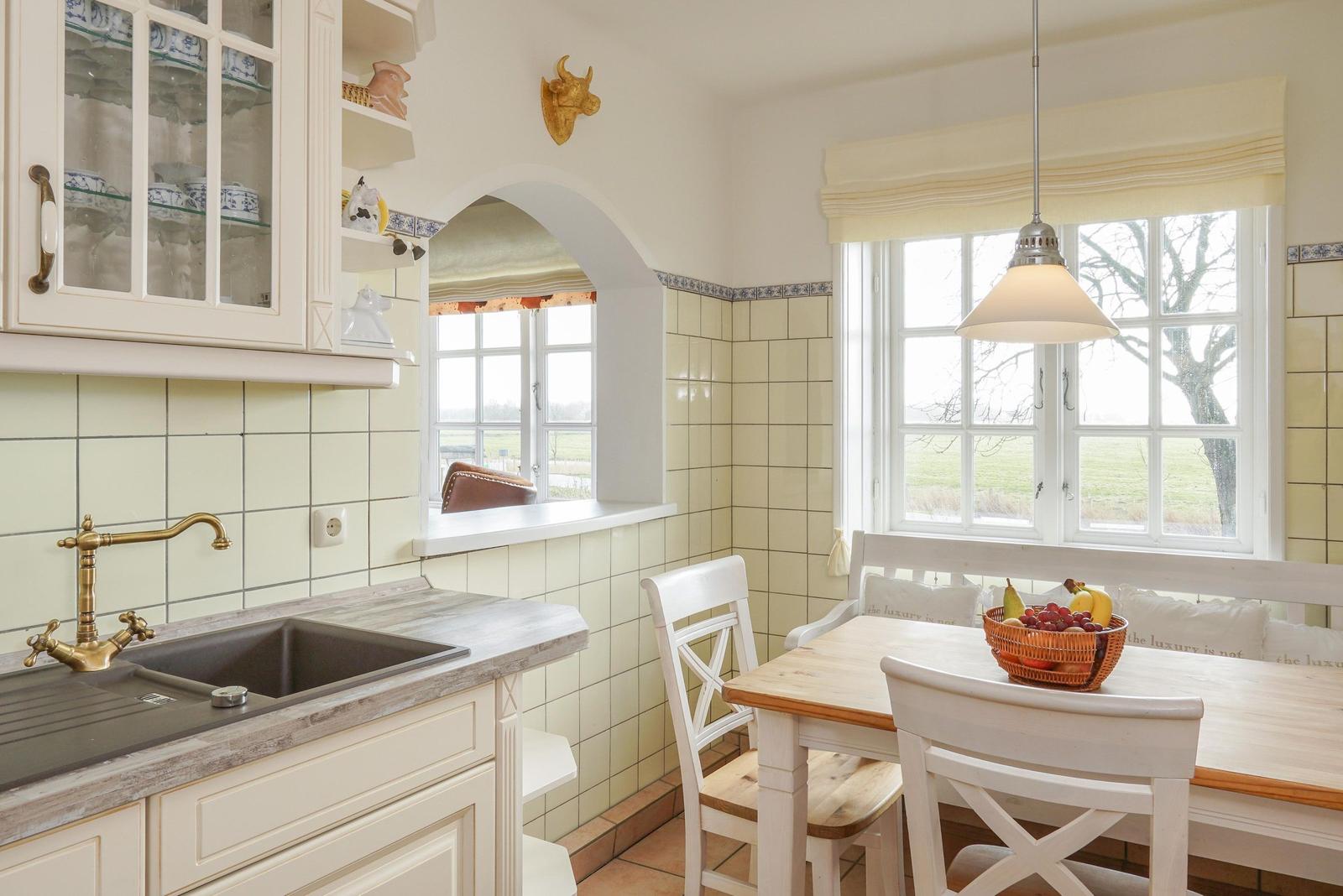 Küche mit Essbereich, weißen Möbeln und Fenstern zum Blick ins Freie.