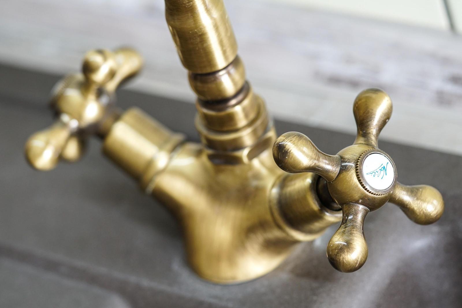 Antik-goldener Wasserhahn mit zwei Kurbeln und Markierung.