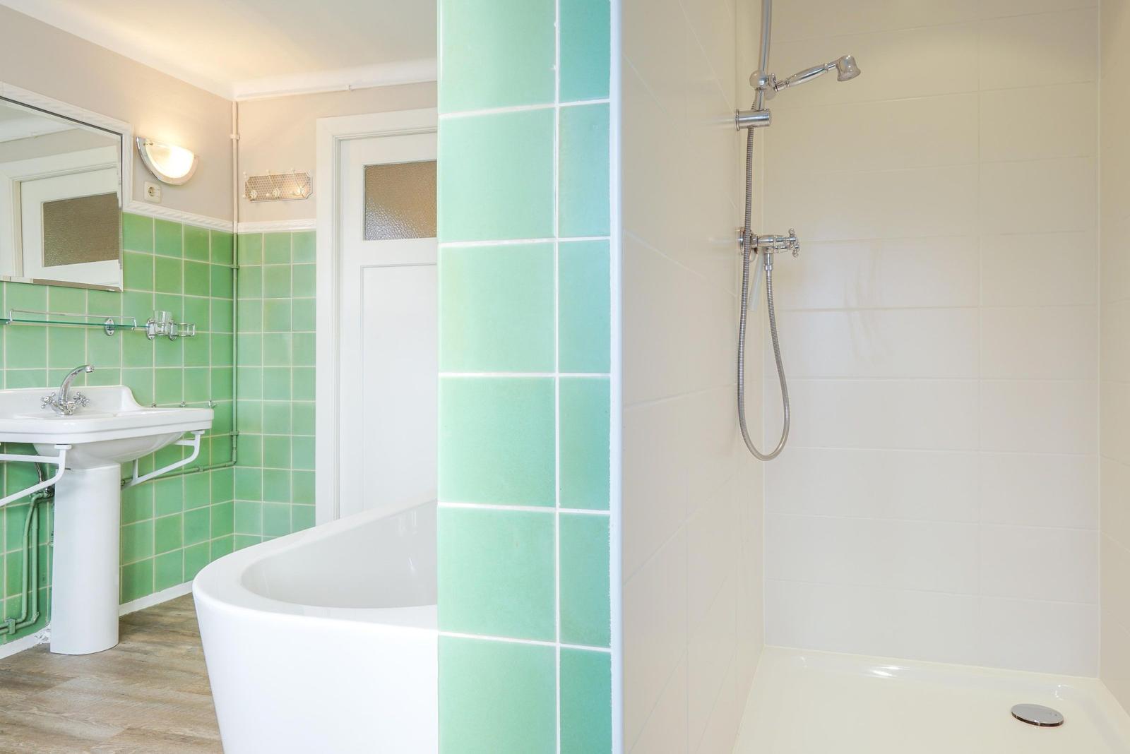 Bad mit Dusche, Badewanne und Waschbecken mit grünen Fliesen