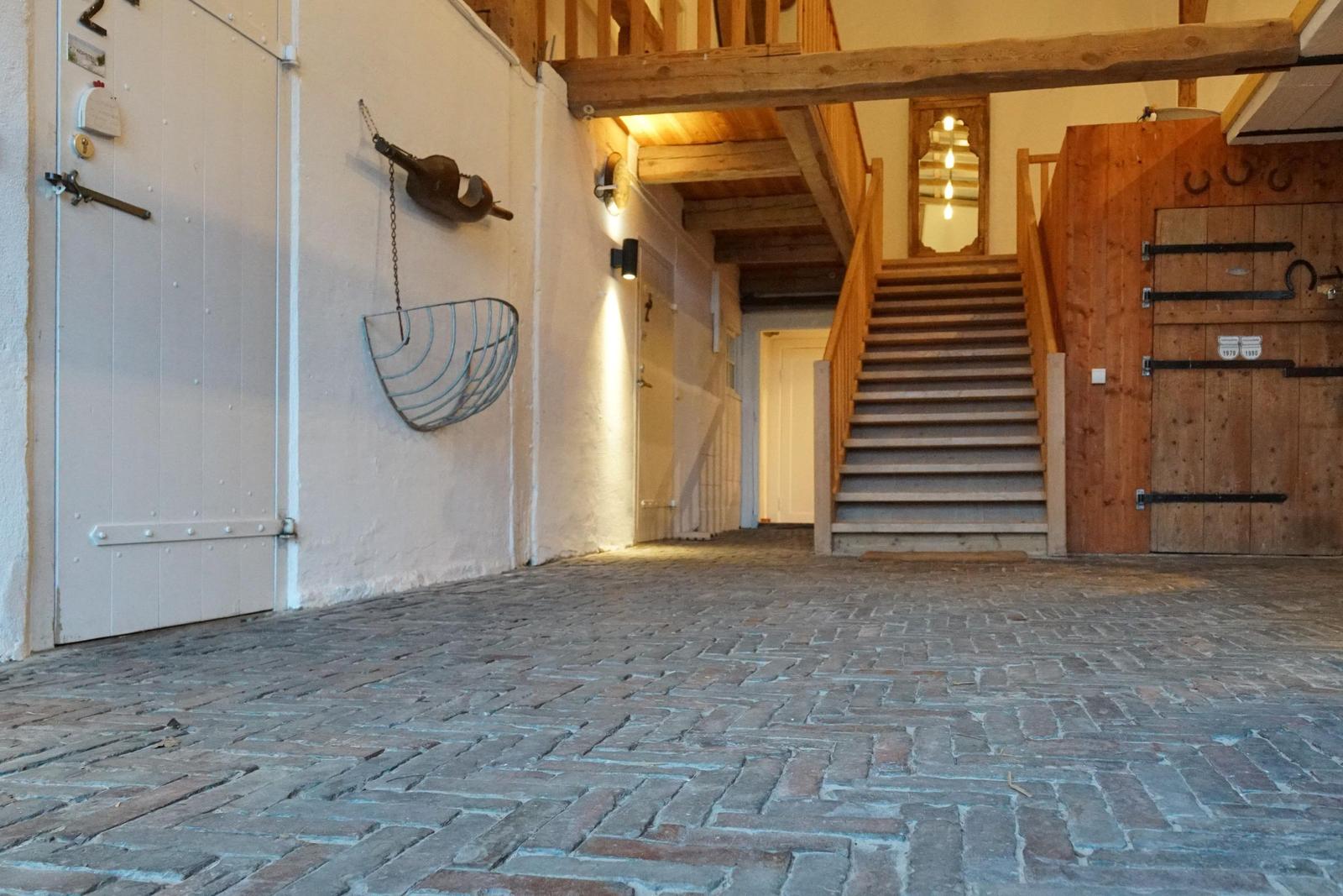 Eingangsbereich mit Steinboden, Holztreppe und rustikalen Dekorationen.