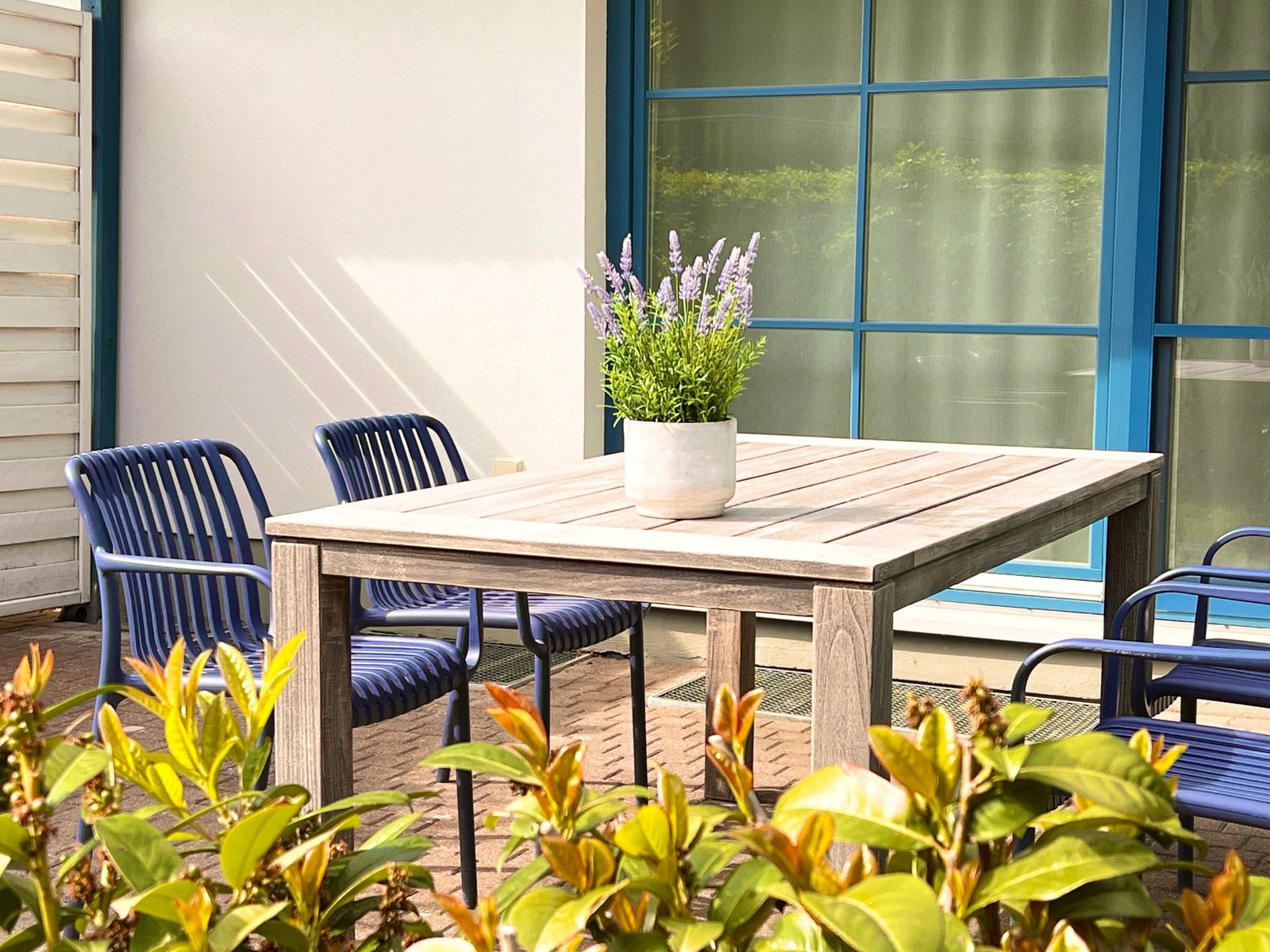 Terrasse mit Holztisch, blauen Stühlen und Lavendel in Topf