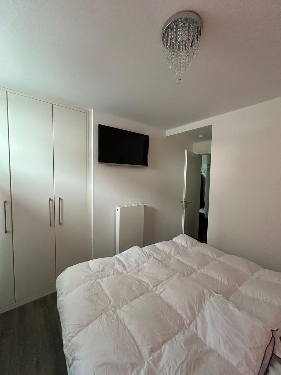 Schlafzimmer mit Bett, Kleiderschrank und Wandfernseher
