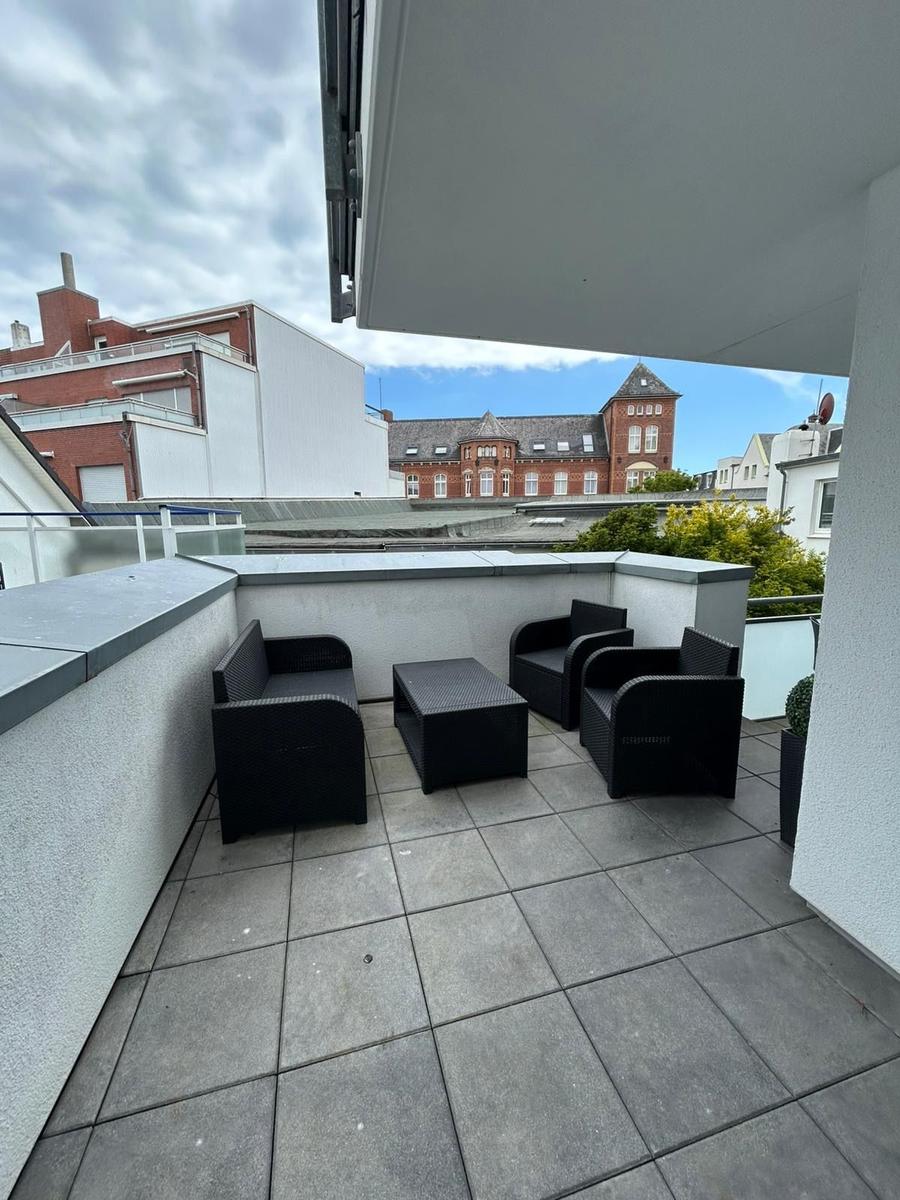 Terrasse mit schwarzer Lounge-Möbelgruppe und Blick auf Gebäude