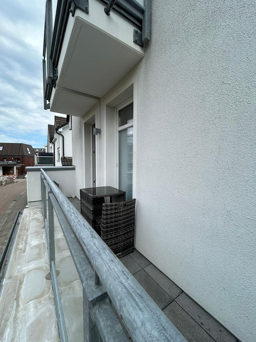 Balkon mit Tisch und zwei Stühlen, weißer Putz, Metallgeländer